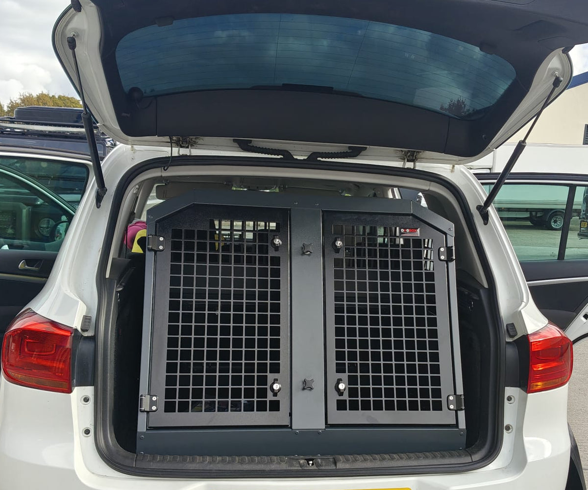 White car with open trunk containing a pet crate